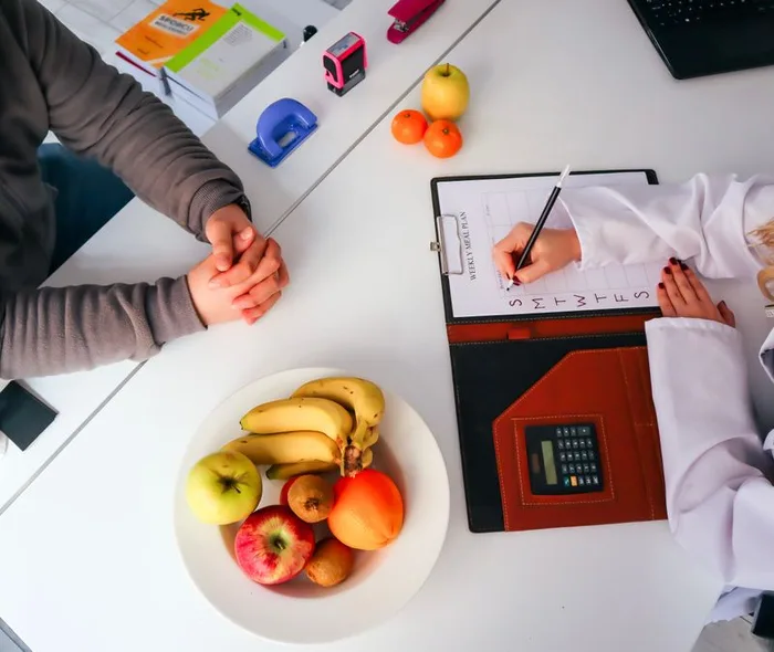 Nutrition consultation scene with a weekly meal plan and fresh fruit
