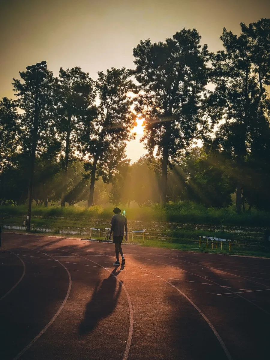 Man walking on a running track at sunrise